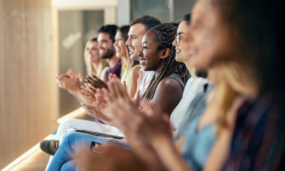 Shot of happy business team clapping after listening the conference while sitting on coworking space.