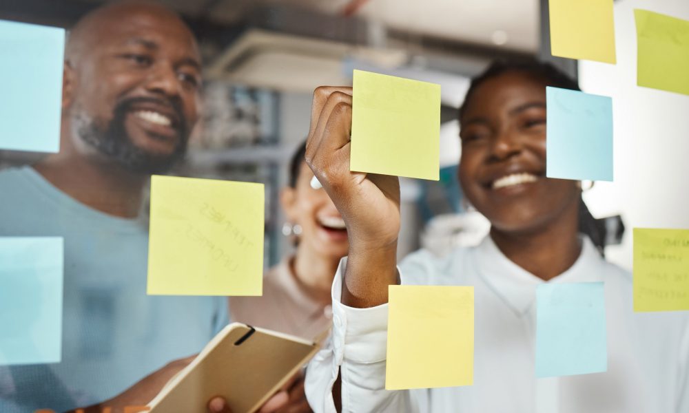 Shot of a group of businesspeople brainstorming with sticky notes on a glass screen.