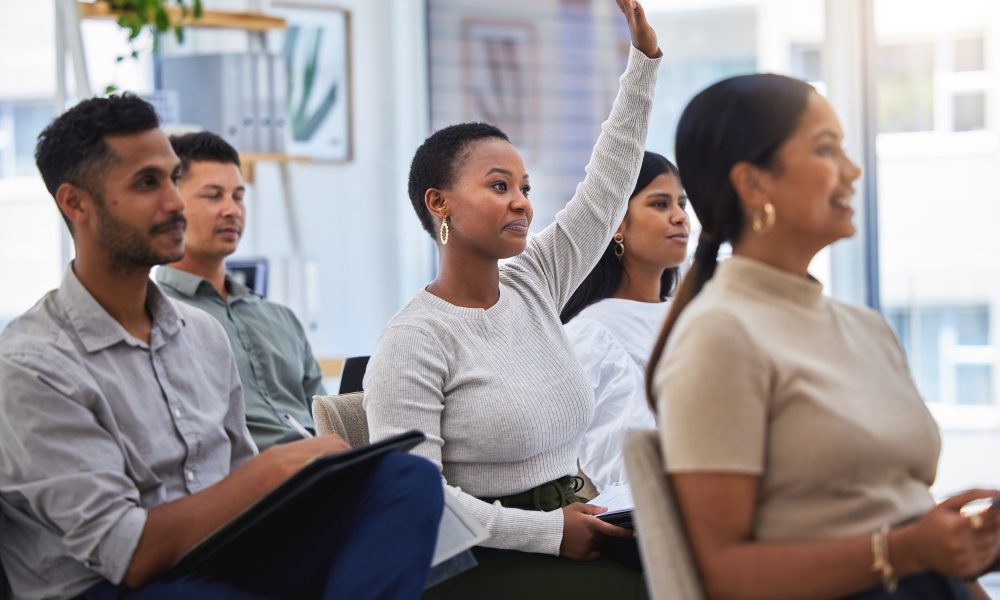 Who wants a promotion. Shot of a young woman raising her hand at work in a modern office