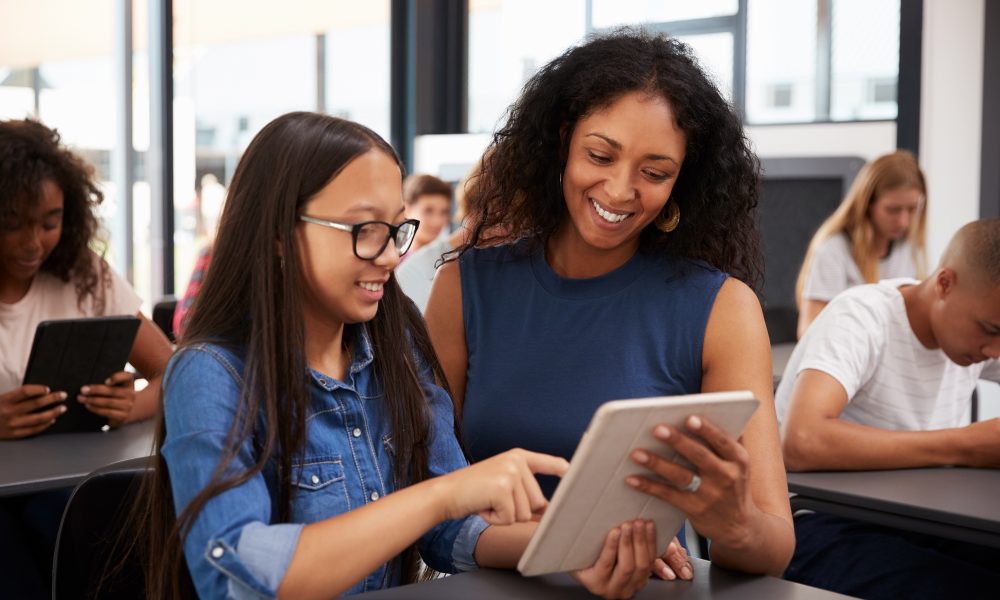 Teacher helping teenage schoolgirl with tablet computer